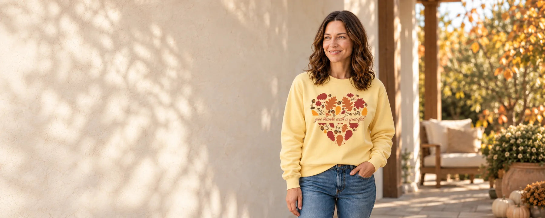 Woman wearing the Butter Grateful Heart Fall sweatshirt on an autumn porch